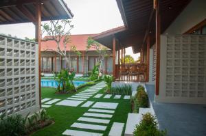 a courtyard of a house with a fence at Omorich Bali Guest House in Canggu