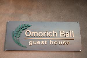a sign for a guest house on a wall at Omorich Bali Guest House in Canggu