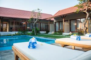 a villa with a swimming pool and two tables at Omorich Bali Guest House in Canggu