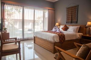 a bedroom with a bed and a large window at Omorich Bali Guest House in Canggu