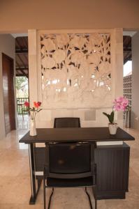 a dining room with a table and some flowers at Omorich Bali Guest House in Canggu