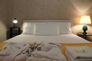 un letto con coperte bianche e asciugamani di La Casetta di Pat a Palermo