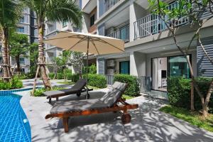 NaiYang beach Title Residencies by My Home Phuket في شاطئ ناي يانغ: فناء مع كرسيين ومظلة بجوار مسبح