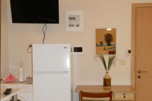 a kitchen with a white refrigerator and a table with a vase at BLUE PHAISTOS APARTMENTS No1 in Moírai