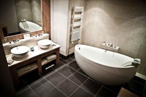 een badkamer met een bad, een wastafel en een spiegel bij Hôtel Les Barmes De l'Ours in Val dʼIsère
