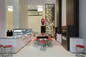 a kitchen with a table and some red stools at Hyatt Place Dubai Jumeirah in Dubai