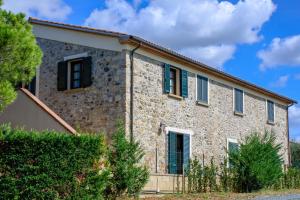 a stone building with black shutters on it at Poggio Picchio in Bibbona