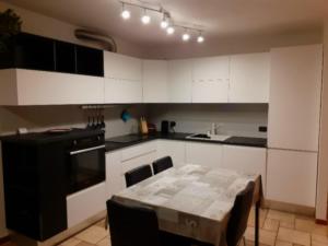 una cocina con armarios blancos y una mesa. en Appartamento a Dimaro in Val di Sole, en Monclassico