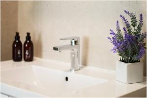 a bathroom sink with a vase of purple flowers at Century City Luxury Two Bedroom Apartment in Cape Town +19 photos