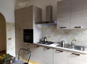 una cucina con armadi bianchi, lavandino e piano cottura di Bel appartement dans la campagne étrusque a Vignanello