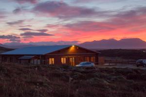 ein Haus auf einem Hügel mit Sonnenuntergang im Hintergrund in der Unterkunft Hotel Stundarfridur in Stykkishólmur