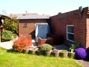 einen Garten mit Pflanzen in einem Hof neben einem Backsteingebäude in der Unterkunft Wohnung Burgstaaken in Fehmarn