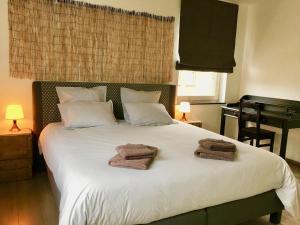 1 dormitorio con 1 cama blanca grande y toallas. en KIPILI SPIRIT HOUSE. en Nivelles