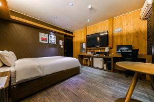 Habitación de hotel con cama, escritorio y TV. en Manhattan Hotel, en Cheongju