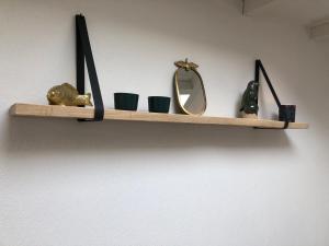 a shelf with cups and a mirror on a wall at Pension Brinkvis in De Koog