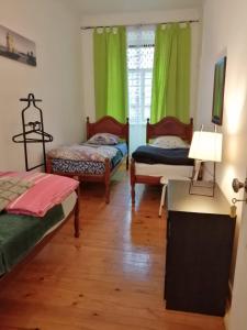 duas camas num quarto com cortinas verdes em LisBangla Guest House em Lisboa mais 29 fotografias