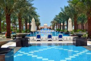 a swimming pool with chairs and palm trees at Luton Vacation Homes - Full Sea View & Huge 2BR , Grandeur Residences, Palm Jumeirah-MC40AB3 in Dubai