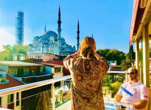 a woman standing on a balcony looking out at a mosque at Charm Hotel in Istanbul