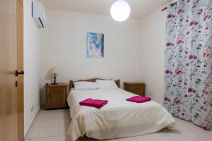 een slaapkamer met een bed met roze handdoeken bij EURO CARISSA FLAT 101 in Larnaka