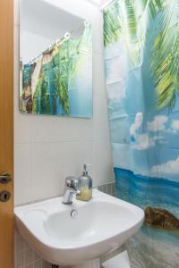 een badkamer met een wastafel en een foto van de oceaan bij EURO CARISSA FLAT 101 in Larnaka