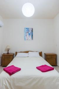 een slaapkamer met een wit bed en 2 handdoeken bij EURO CARISSA FLAT 101 in Larnaka