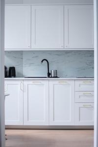 a white kitchen with white cabinets and a sink at Apartament Jola in Sopot