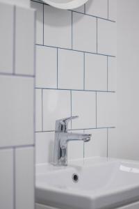 a sink in a bathroom with white tiled walls at Apartament Jola in Sopot