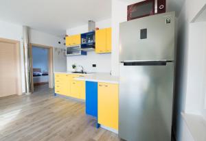 a kitchen with yellow cabinets and a stainless steel refrigerator at Apartman GRC in Dugo Selo