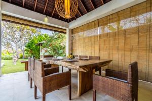 een eetkamer met een grote houten tafel en stoelen bij Pristine Yuyu Villa Balian in Balian