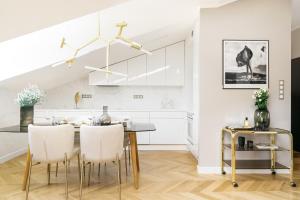 a white kitchen with a dining table and chairs at Penthouse Orzeszkowa by LoftAffair in Krakow