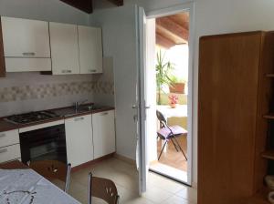 una cocina con armarios blancos y una puerta abierta a un patio en Soggiornare a Cagliari, en Cagliari