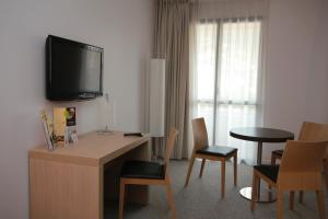 Habitación de hotel con escritorio y TV en la pared. en Esatitude Hotel, en Niza