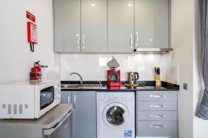 a kitchen with a microwave and a washing machine at ImpervillaStudio - Vilamoura City Centre in Quarteira