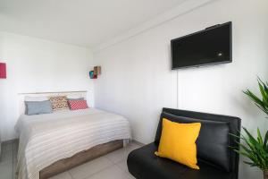 a bedroom with a bed and a couch and a flat screen tv at ImpervillaStudio - Vilamoura City Centre in Quarteira