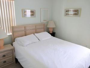 a bedroom with a bed with white sheets and two lamps at Seahorse Landing #503 Gulf Front Vacation Condo in Cedar Key