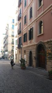 eine Person, die eine Straße entlang geht, neben einem rosa Gebäude in der Unterkunft Kriò Suite in Salerno