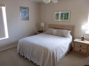 a bedroom with a white bed and two tables and two windows at Seahorse Landing #503 Gulf Front Vacation Condo in Cedar Key
