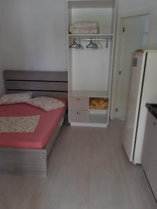 um pequeno quarto com uma cama e um frigorífico em Frente Mar em Florianópolis