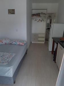 um pequeno quarto com uma cama e uma geladeira em Frente Mar em Florianópolis