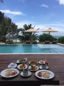 uma mesa com pratos de comida ao lado de uma piscina em Villa Blu em Tangalle