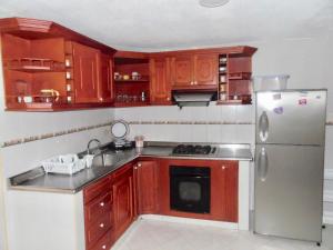 cocina con armarios de madera y nevera de acero inoxidable en Karey 906 Rodadero, en Santa Marta