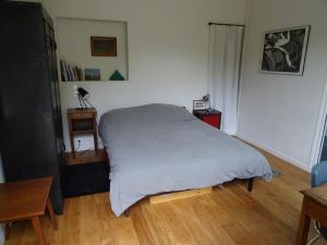 a bedroom with a white bed and a wooden floor at Chambre d'hôtes sur jardin acces PMR in Caen