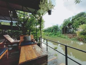 eine Holzbank auf einem Deck neben einem Fluss in der Unterkunft Baan Canalee (บ้านคานาลี) in Phra Nakhon Si Ayutthaya