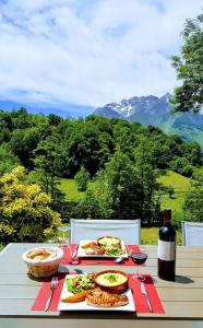 una mesa con platos de comida y una botella de vino en Le Pic de Pan - Auberge & Gîtes en Arrens-Marsous