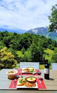 a table with plates of food and a bottle of wine at Le Pic de Pan - Auberge & Gîtes in Arrens-Marsous