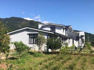a white house with mountains in the background at Bi La Homestay in Luye +38 photos