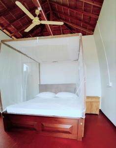 Cama en habitación con ventilador de techo en Exotic Beach Hotel, en Arugam Bay