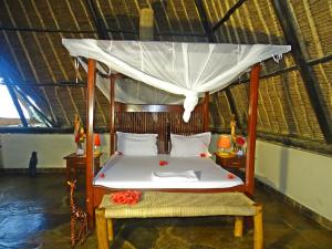 a bedroom with a canopy bed with flowers on it at Diani-Paradise-Villas in Diani Beach