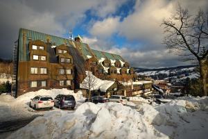 parking pokryty śniegiem przed budynkiem w obiekcie Sporthotel Bohemia w Rokitnicach nad Izerą