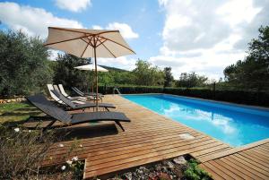 a deck with chairs and an umbrella next to a swimming pool at Borgo dei Fondi in Siena